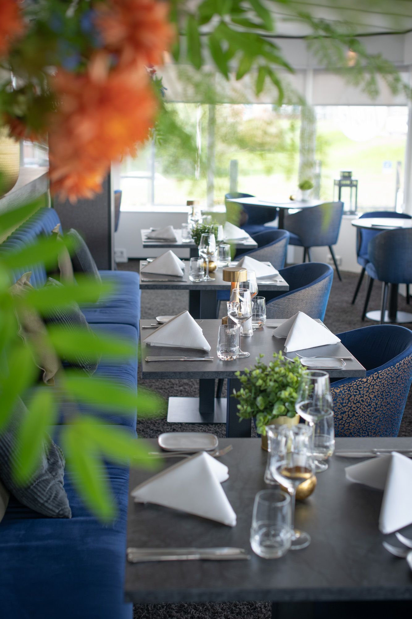 Interieur van het restaurant Churchill Hotel Terneuzen, stoelen met blauwe bekleding, tafels met glaswerk. 