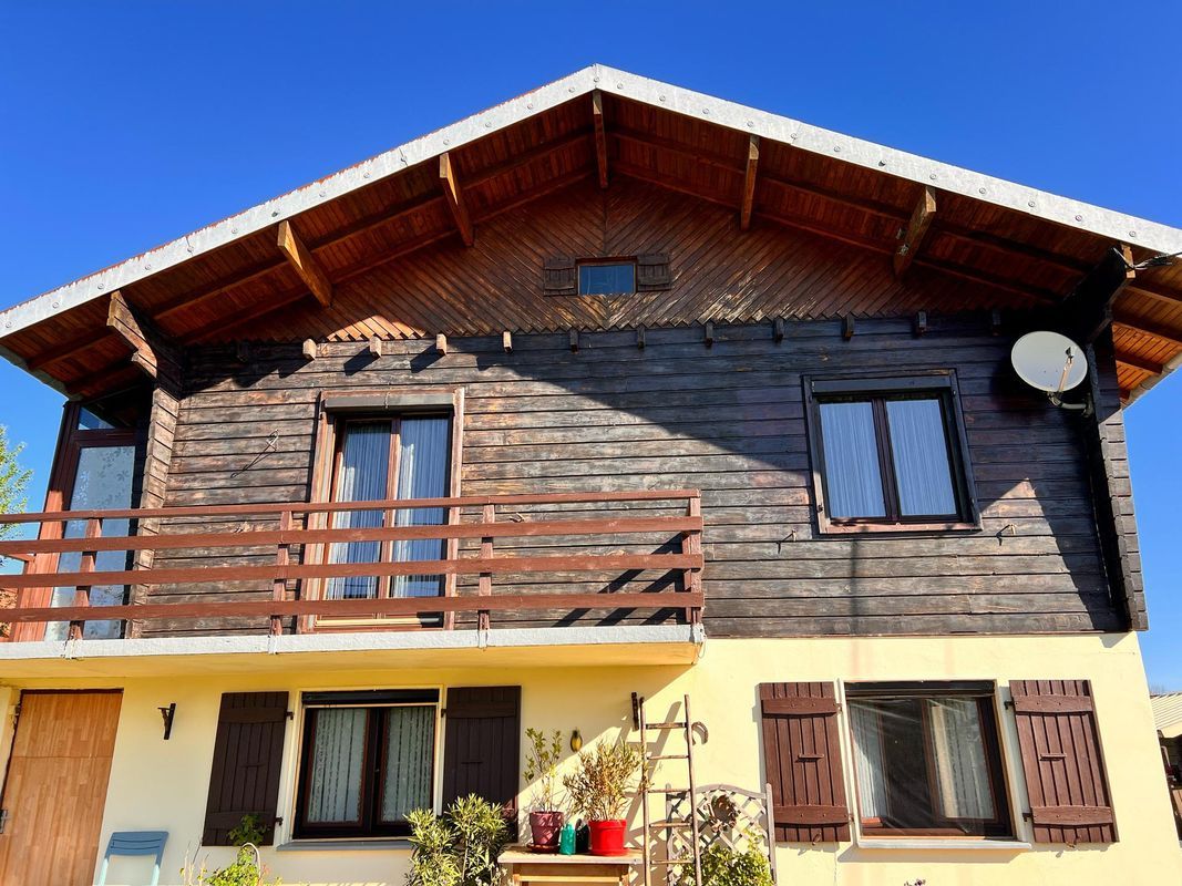 Une maison avec un bardage en bois à l'étage.