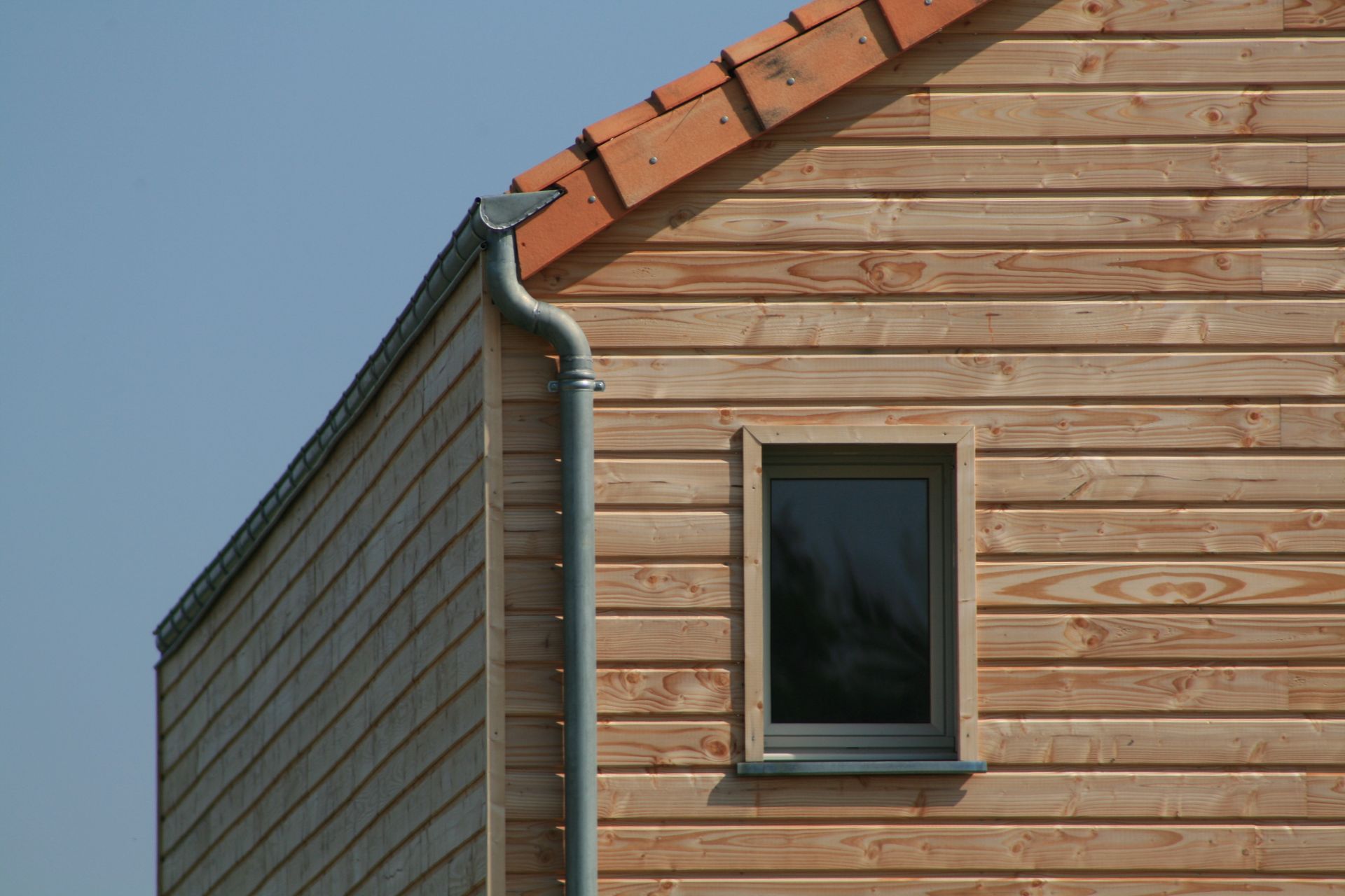 Un bardage en bois et une descente de gouttière.