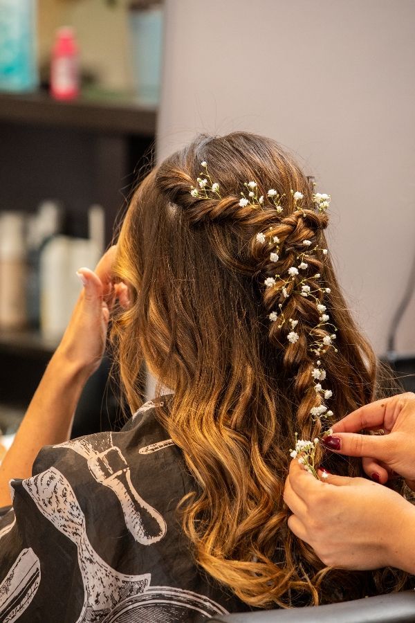 Une femme se fait coiffer avec des fleurs dans un salon.
