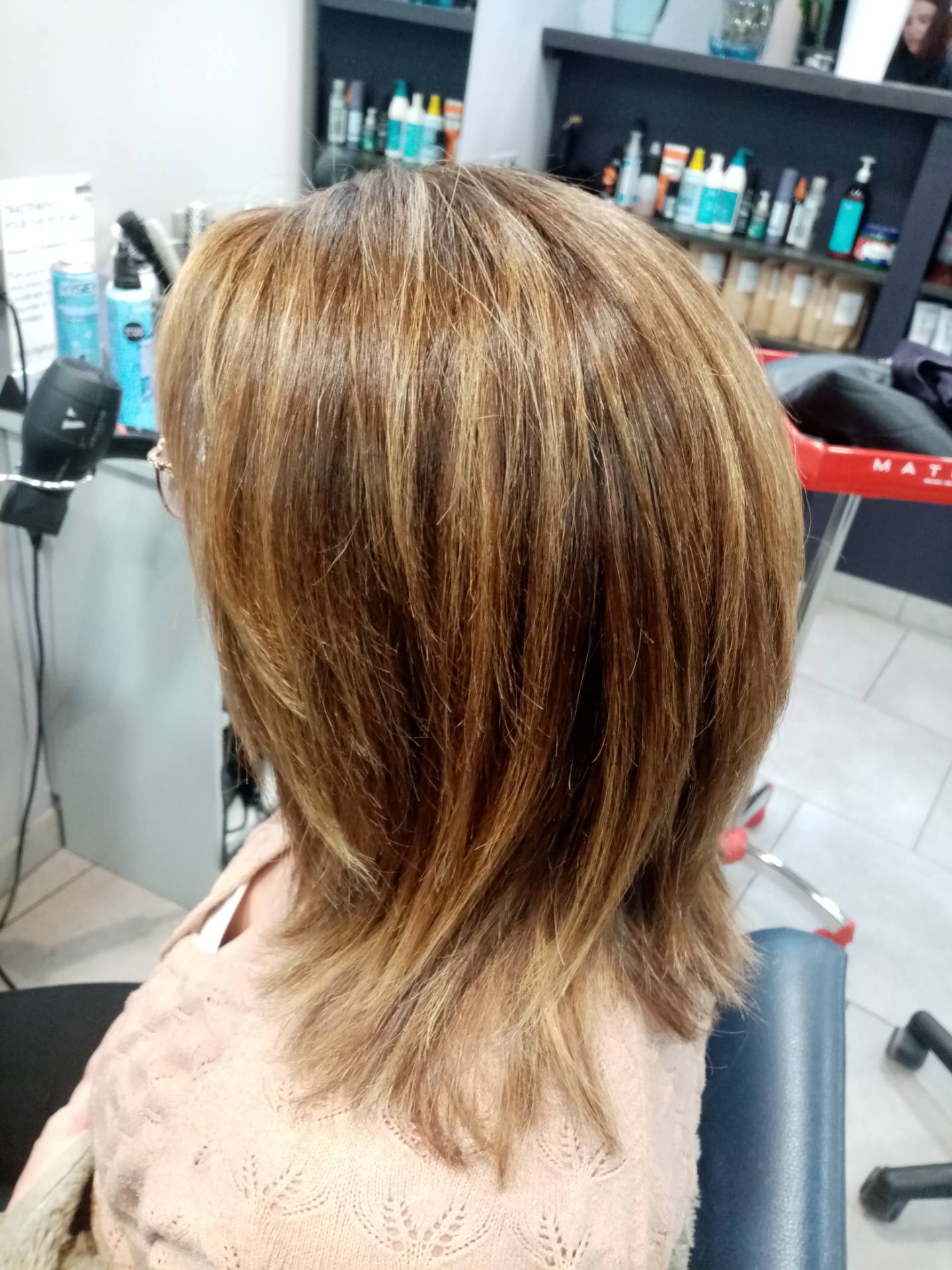 Femme aux cheveux bruns dégradés et méchés dans un salon de coiffure.