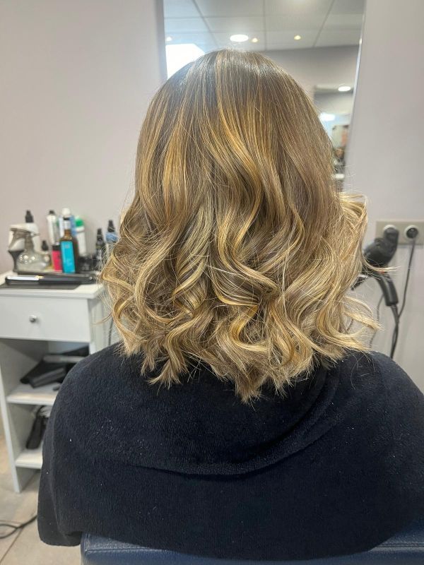 Cheveux ondulés mi-longs avec reflets dorés ; style salon.