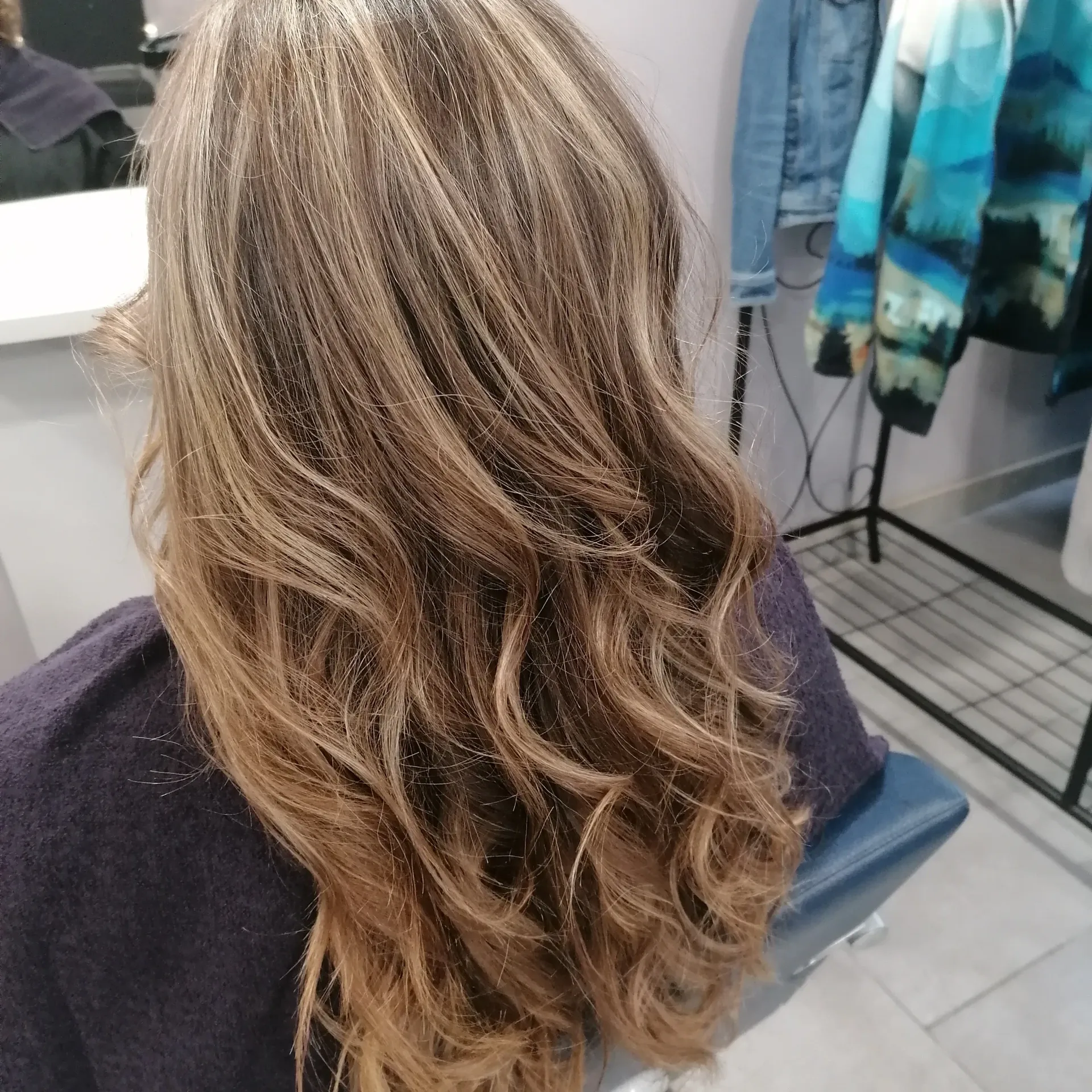 Femme aux cheveux bruns longs et ondulés dans un salon.