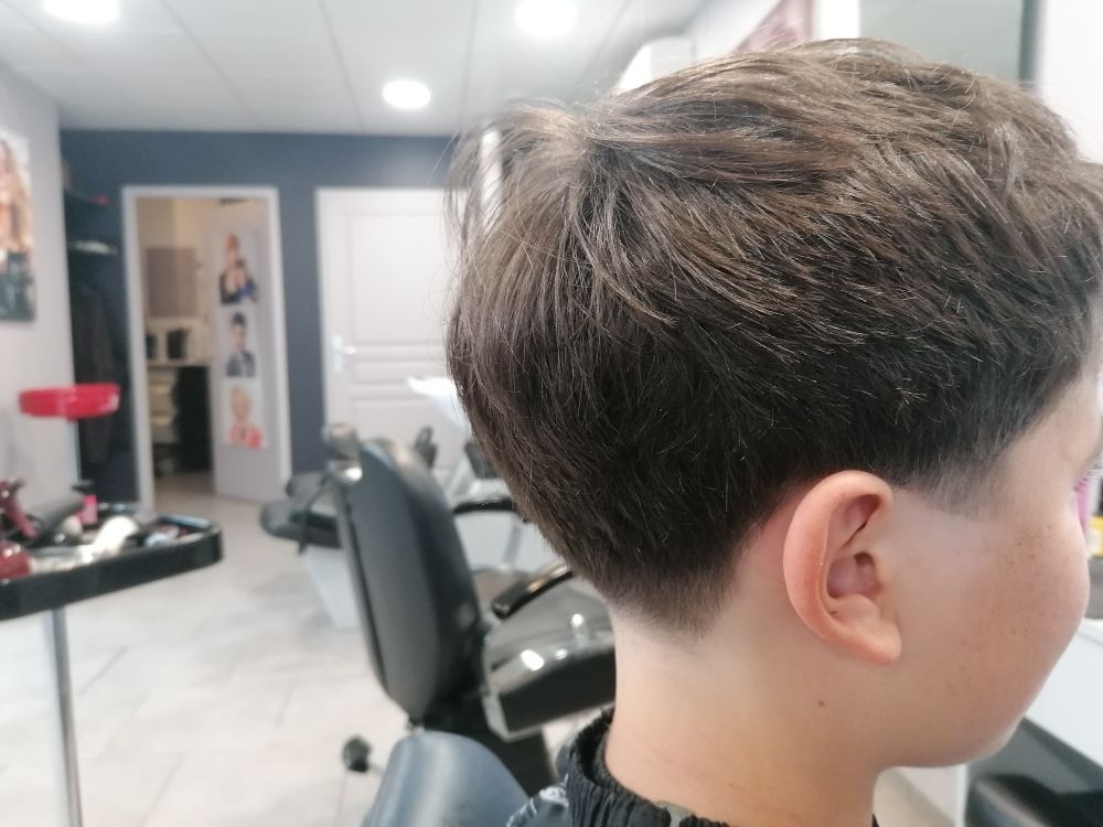 Garçon aux cheveux courts, chez le coiffeur, vue de profil. Côtés décolorés, haut court.