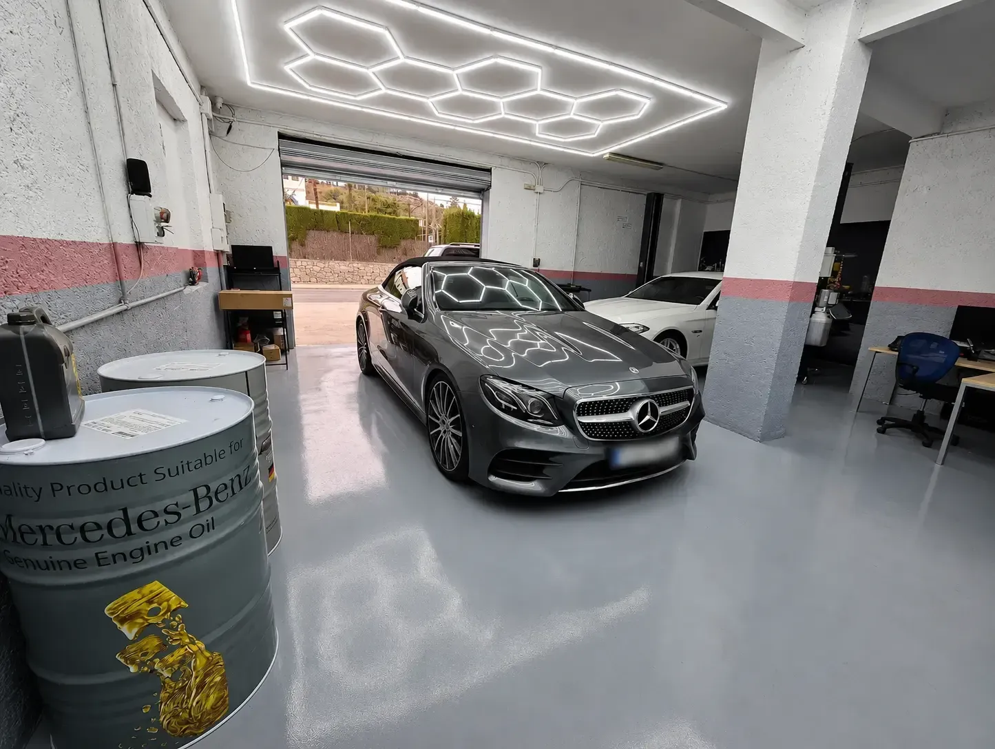 Un Mercedes-Benz descapotable negro en una luminosa sala de exposición con iluminación hexagonal en el techo.