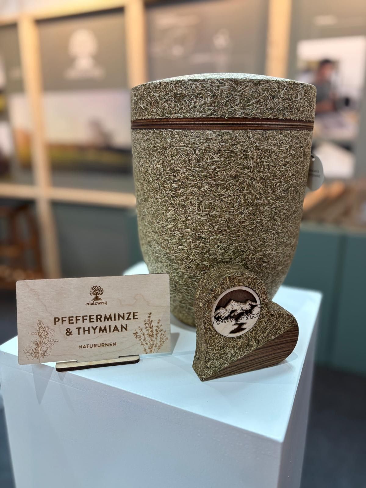 Peppermint and thyme display jar with matching label on a light blue pedestal.