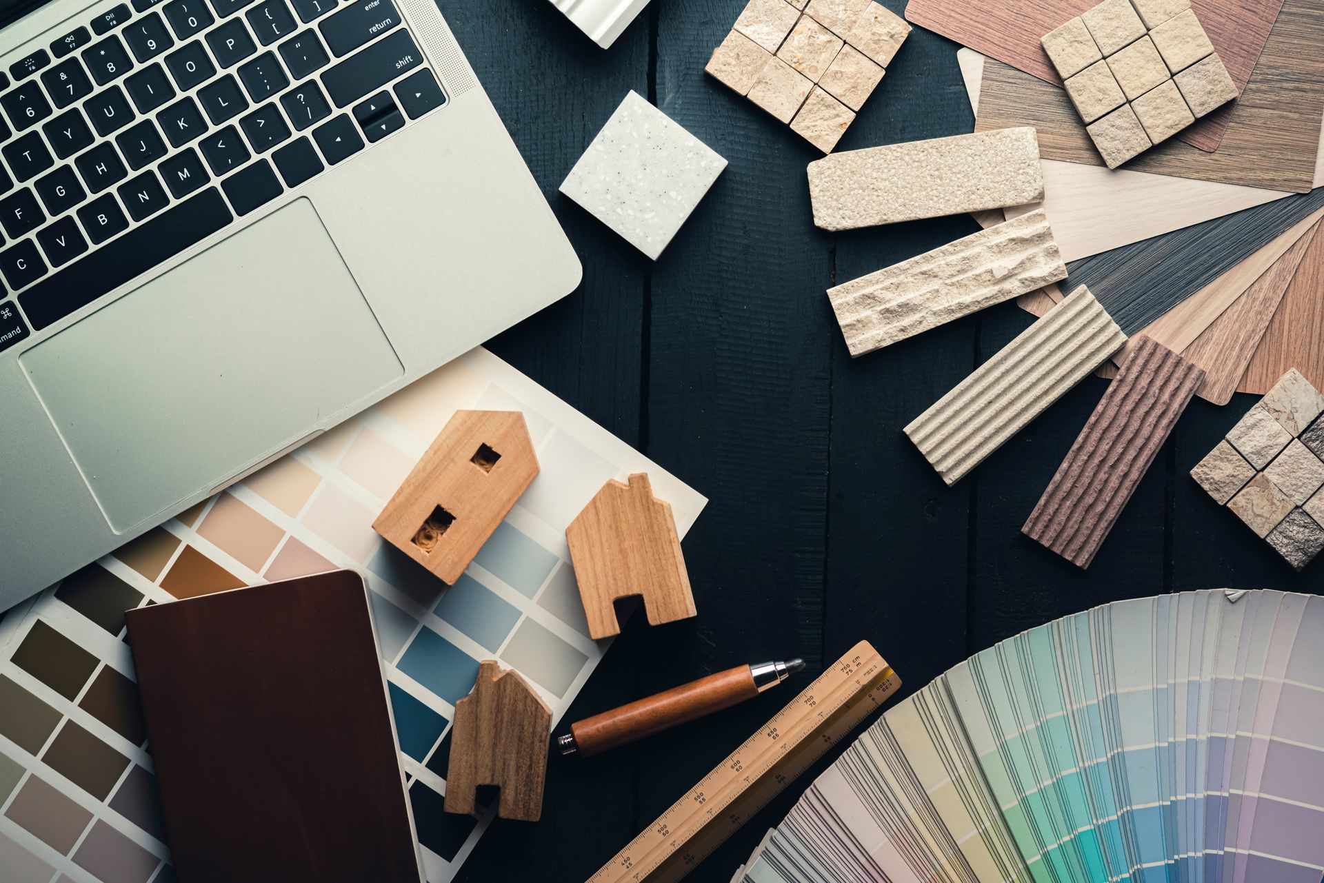 Ordinateur portable, échantillons de peinture, blocs de bois et règles sur une surface noire.