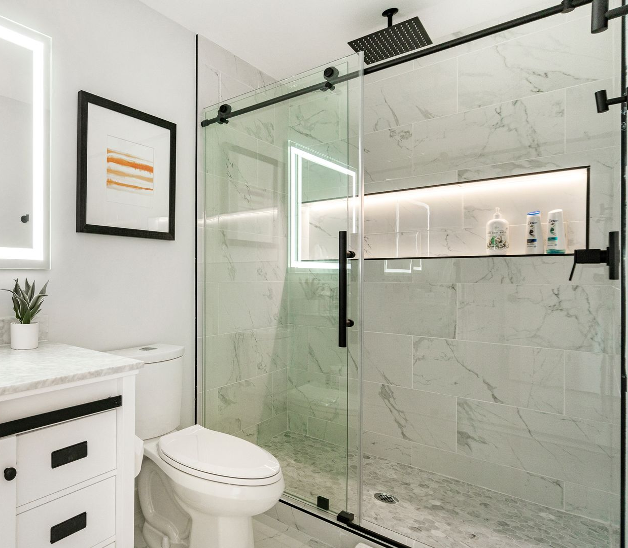 Salle de bains moderne avec douche en verre, murs en marbre et touches de noir.