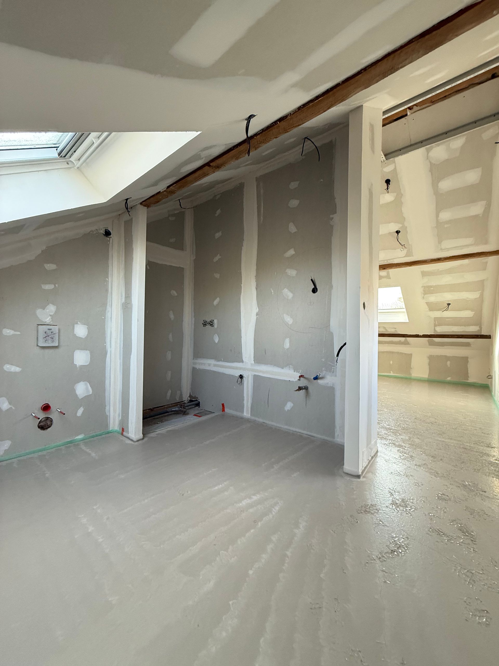 Pièce en travaux avec cloisons sèches, câblage apparent et sol en béton.