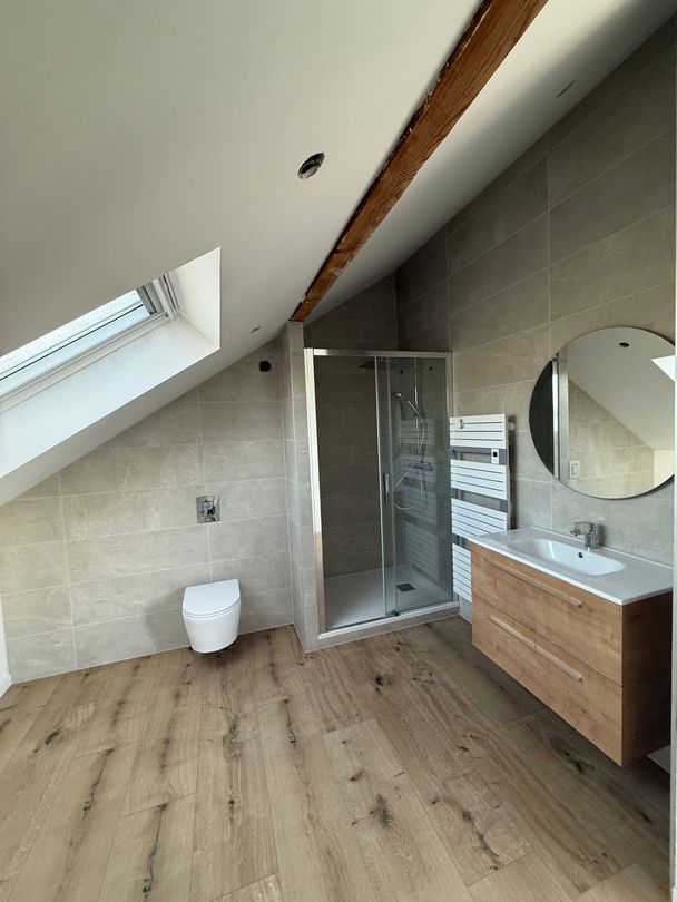 Intérieur d'une pièce en cours de rénovation, avec murs apparents, poutres de soutien et matériaux de construction.