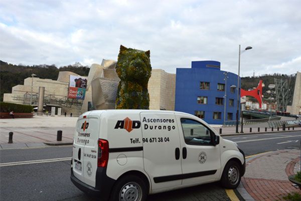Una camioneta blanca está estacionada frente a un edificio azul.