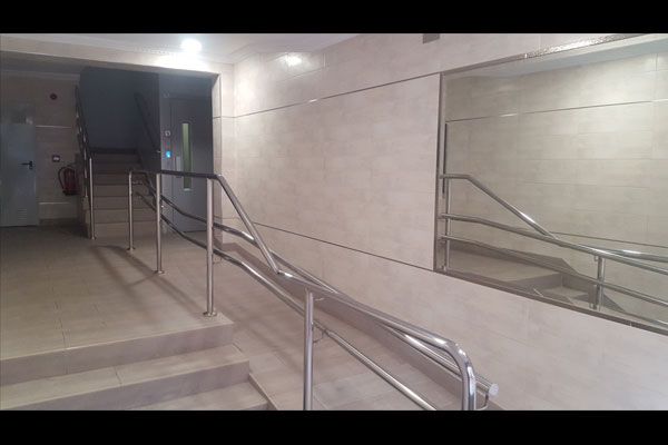 Una escalera con barandilla de metal y un espejo en la pared.