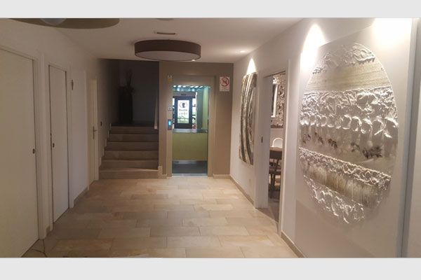 Un pasillo con escaleras y una escultura en la pared.