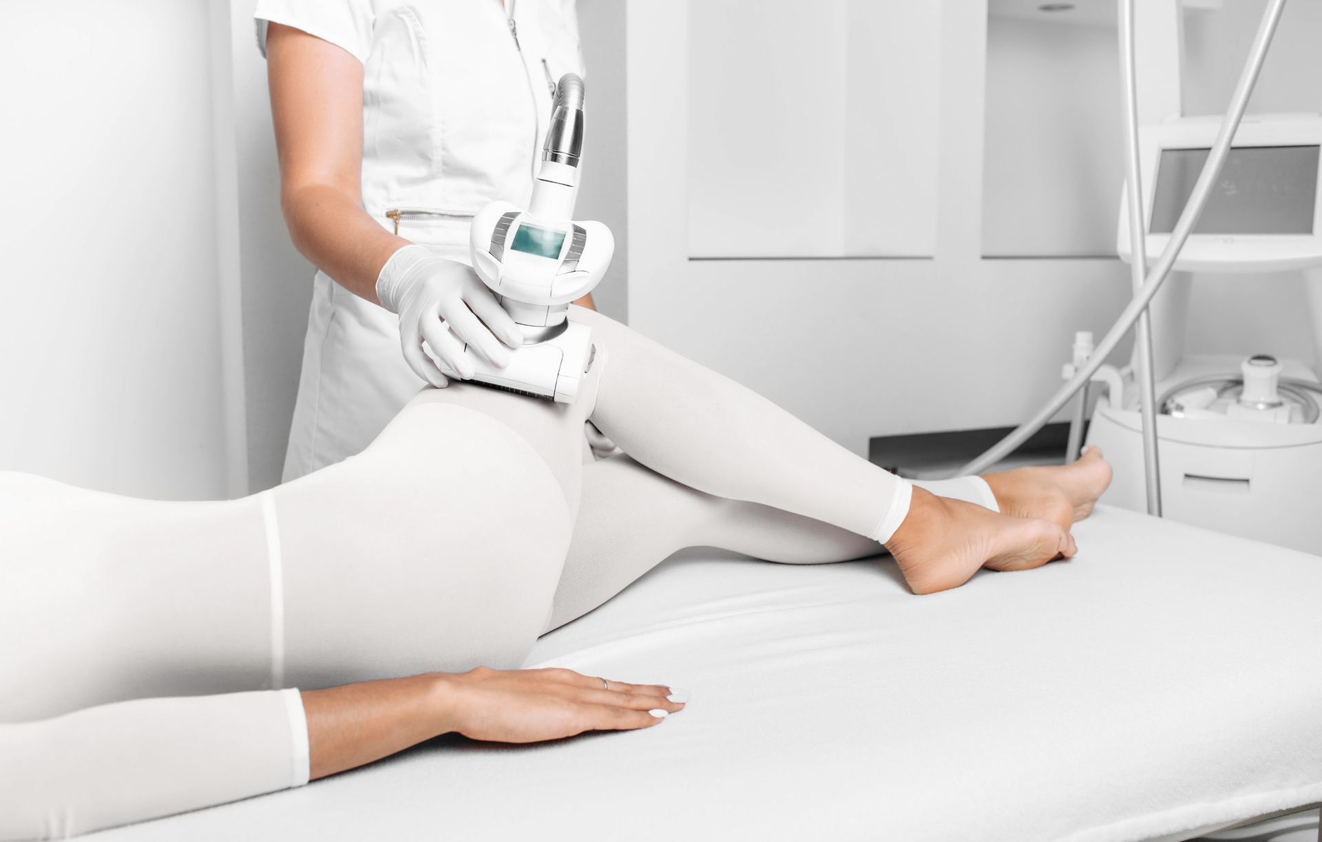 Persona que recibe un tratamiento de contorno corporal con un dispositivo portátil en la pierna en una clínica.