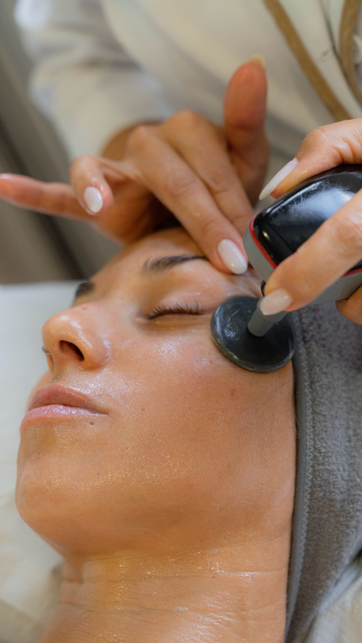 Persona que administra un tratamiento de piernas con un dispositivo portátil a un cliente en un spa.