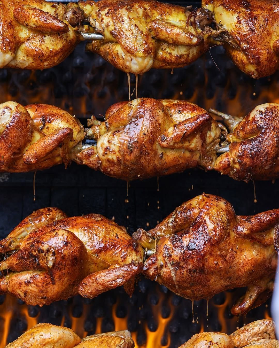 Pollos asados sobre las llamas, chorreando jugos.