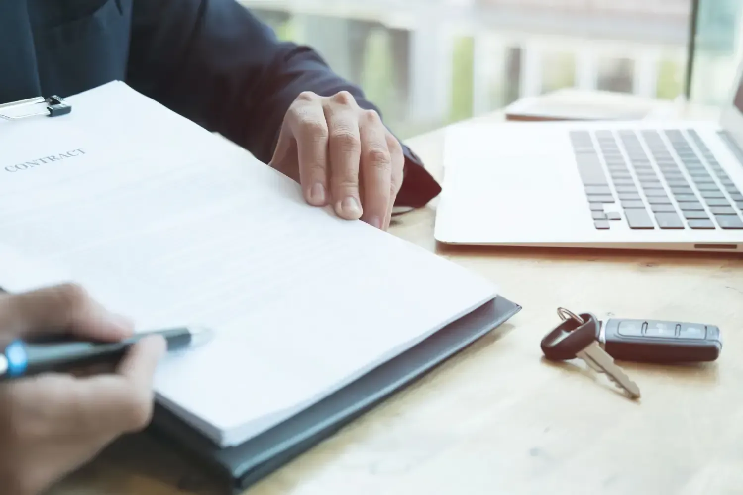 Una persona está sentada en una mesa con una computadora portátil y un portapapeles.