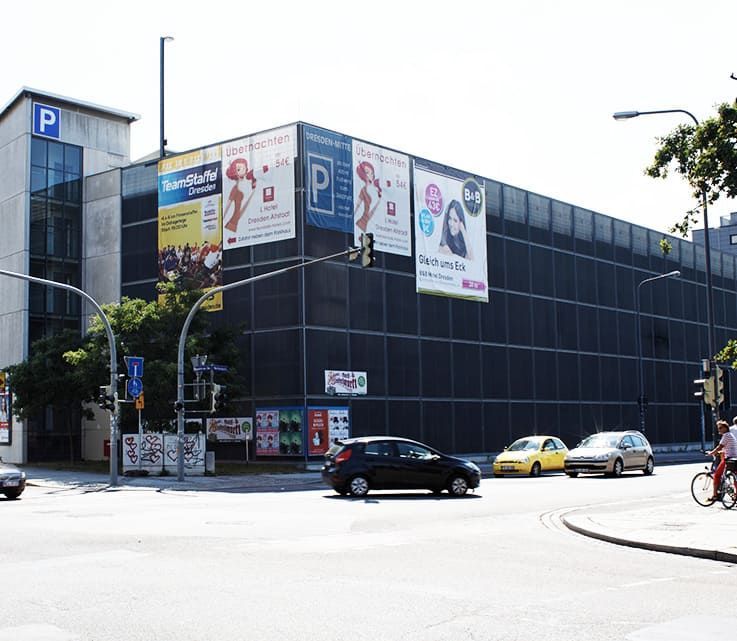 Ein Auto fährt eine Straße vor einem Parkhaus entlang