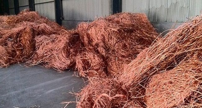 Montones de restos de alambre de cobre, de color marrón rojizo, que descansan sobre un suelo de hormigón en el interior.