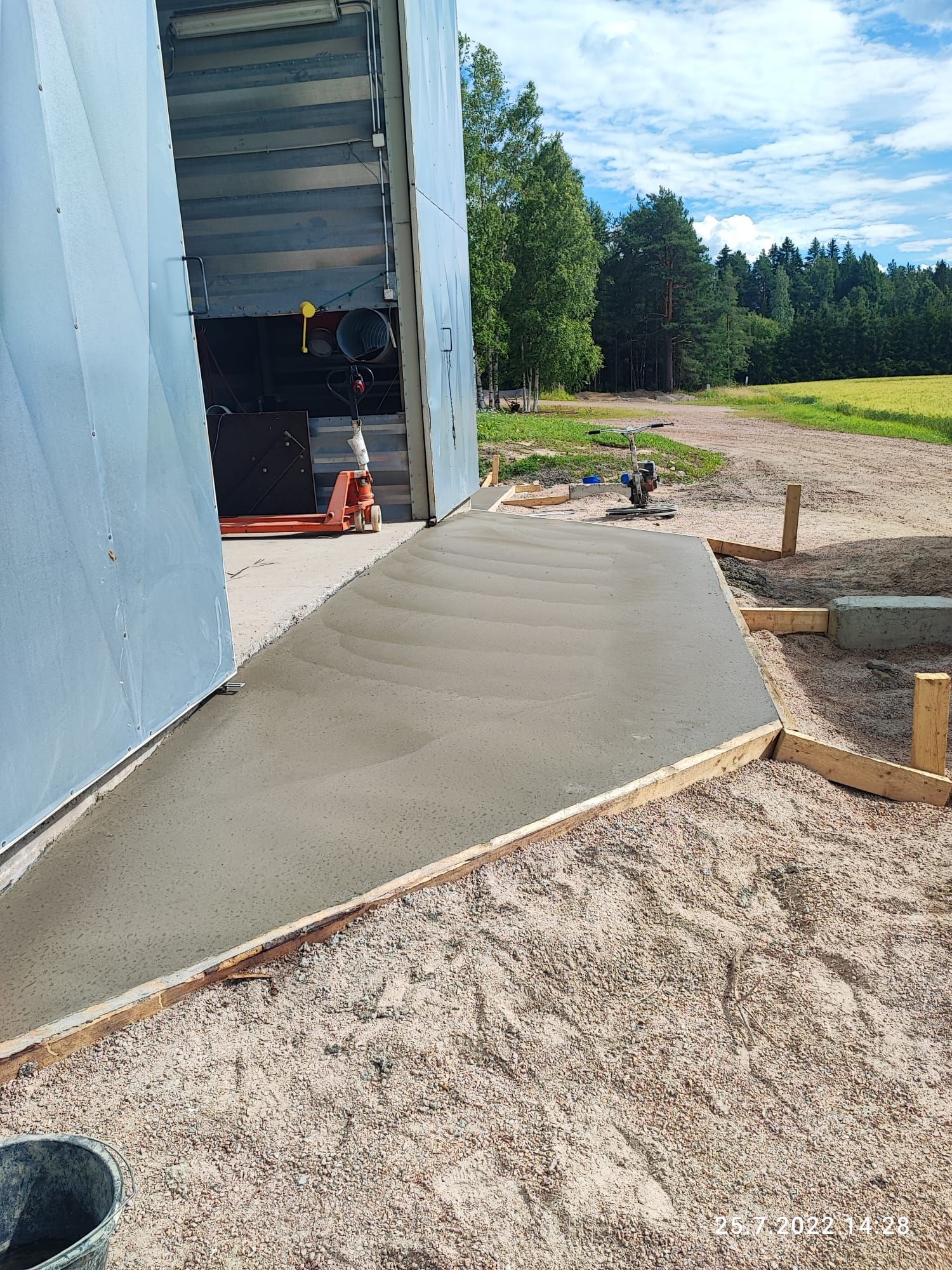Vastavalettu betoniramppu rakennuksen vieressä, puulaudoilla kehystetty. Aurinkoinen ulkoympäristö.