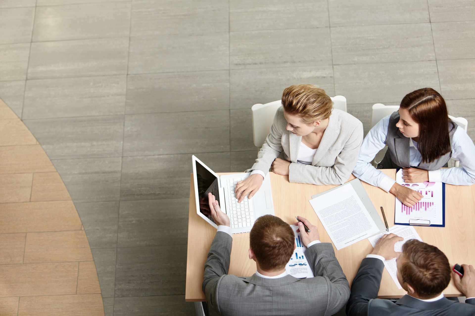Quatre personne autour d'une table regardant un ordinateur portable.