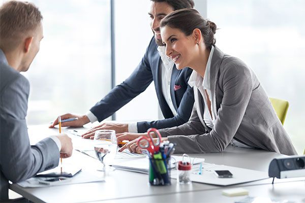 Trois personnes en costume montrant des documents sur la table.