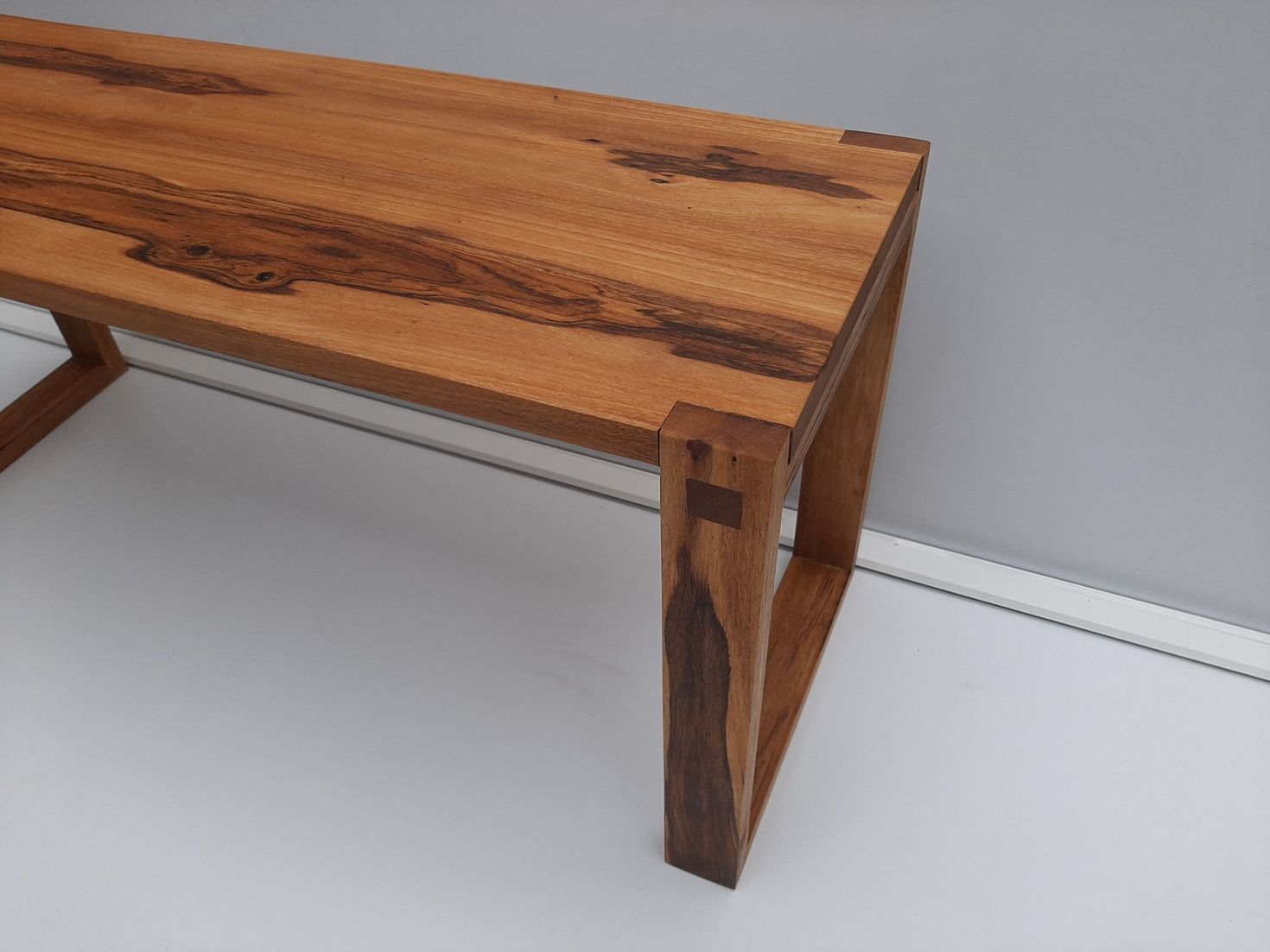 Banco de madera con patas cuadradas, veta de madera natural y juntas de cola de milano.