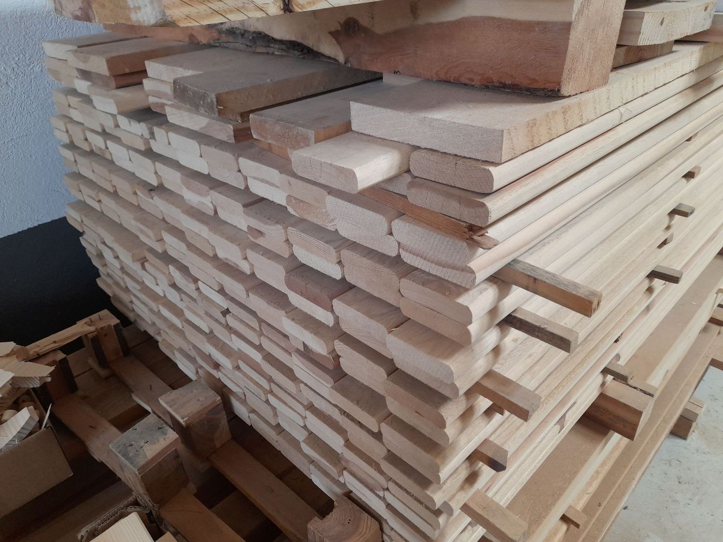 Pila de tablones de madera de color claro sobre un palé.
