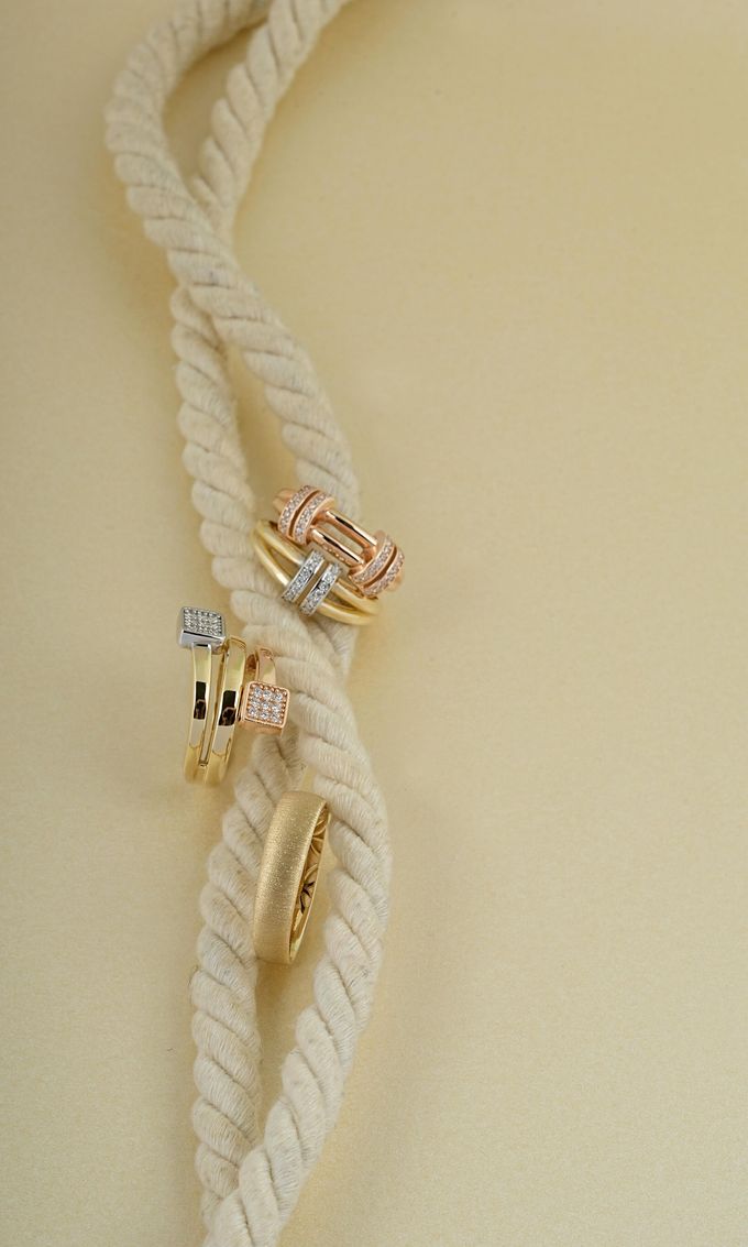 Cuerda trenzada color crema con pequeños adornos de oro y cristal sobre un fondo beige.