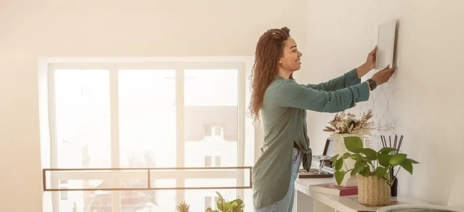 Persona pintando una pared en una habitación en renovación, rodeada de latas de pintura..