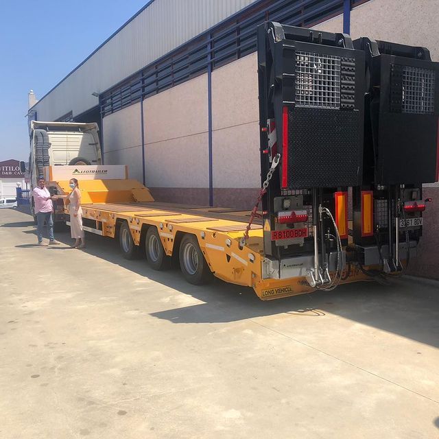 Un camión amarillo con un remolque negro está estacionado frente a un edificio.