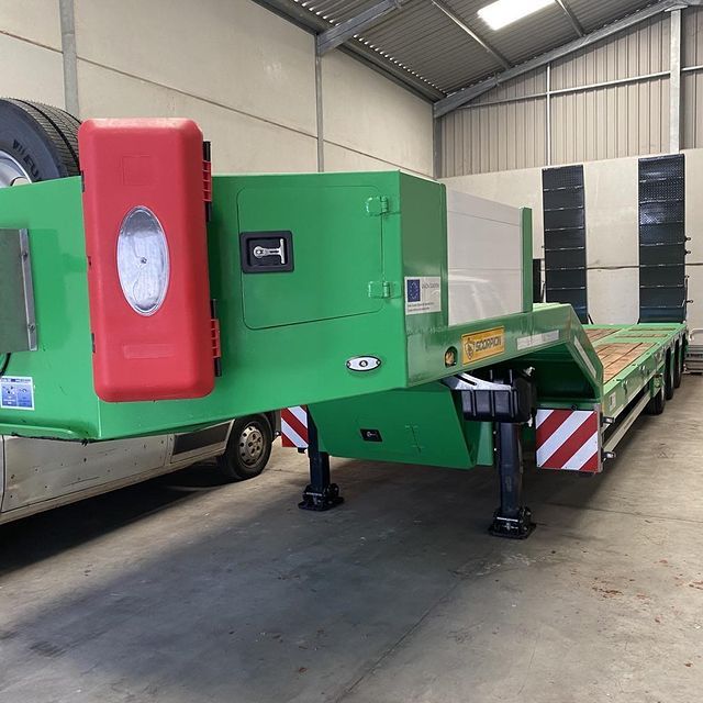 Un remolque verde está estacionado en un almacén al lado de un camión.