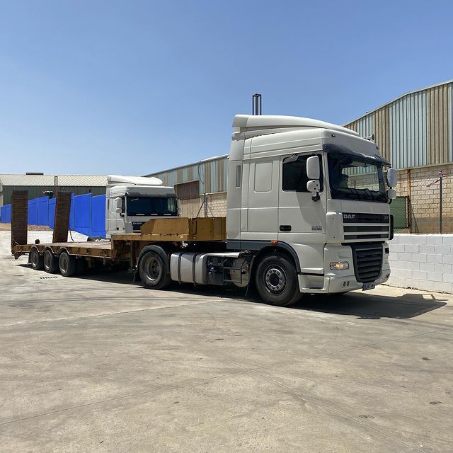 Un camión semirremolque blanco con un remolque acoplado está estacionado en un estacionamiento.