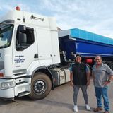 Dos hombres están parados frente a un camión semirremolque.