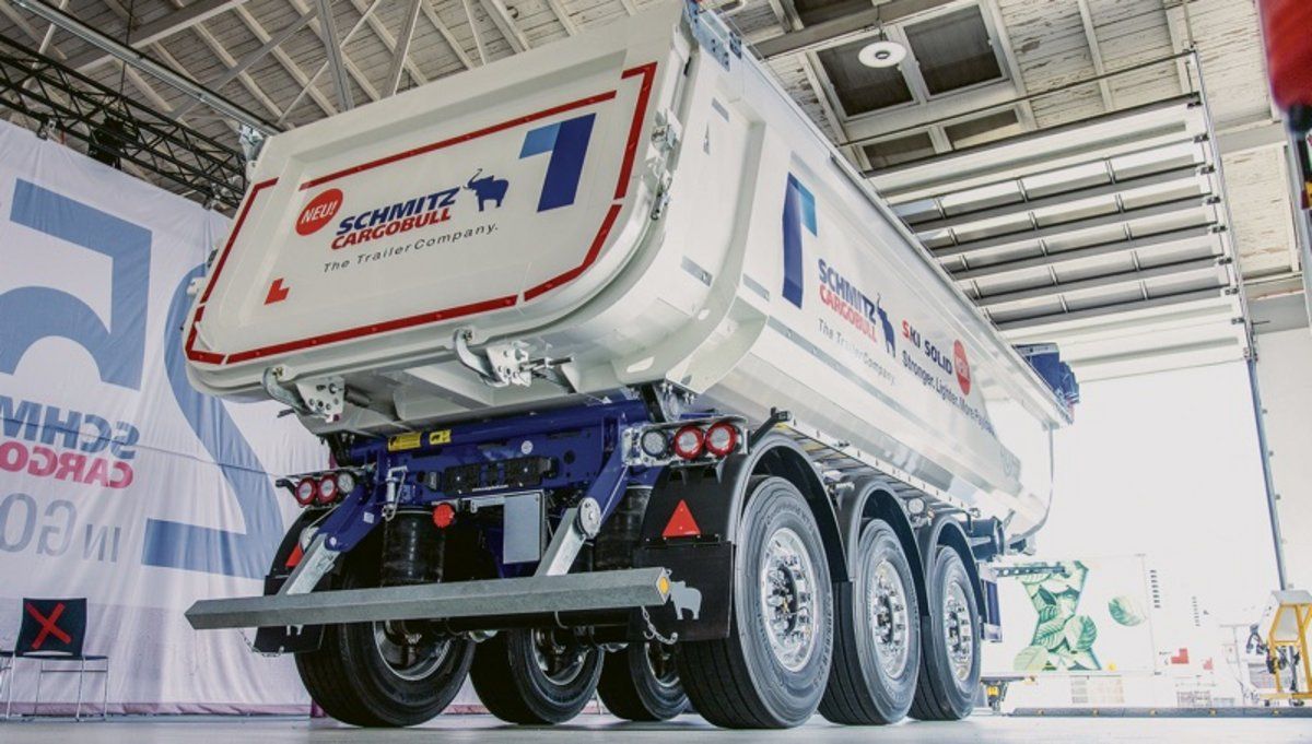 Un camión semirremolque blanco y azul está estacionado en un almacén.