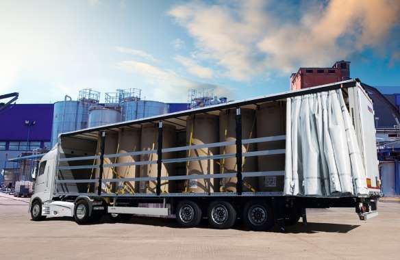 Un camión semirremolque con remolque está estacionado frente a un edificio.