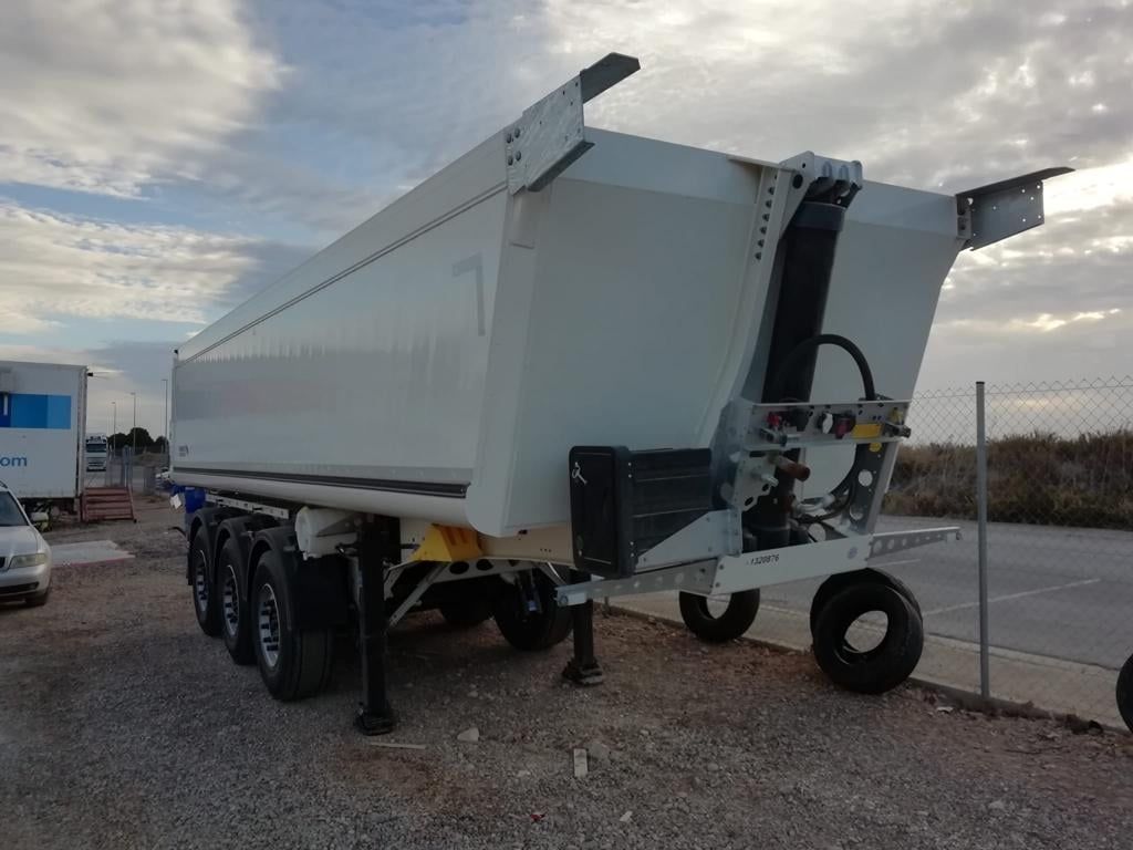 Un camión volquete blanco está estacionado en un lote de grava.