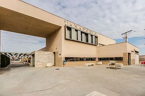 Un edificio grande con muchas ventanas y muchos bancos delante de él.