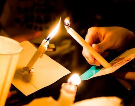 Una persona sostiene dos velas encendidas en sus manos.