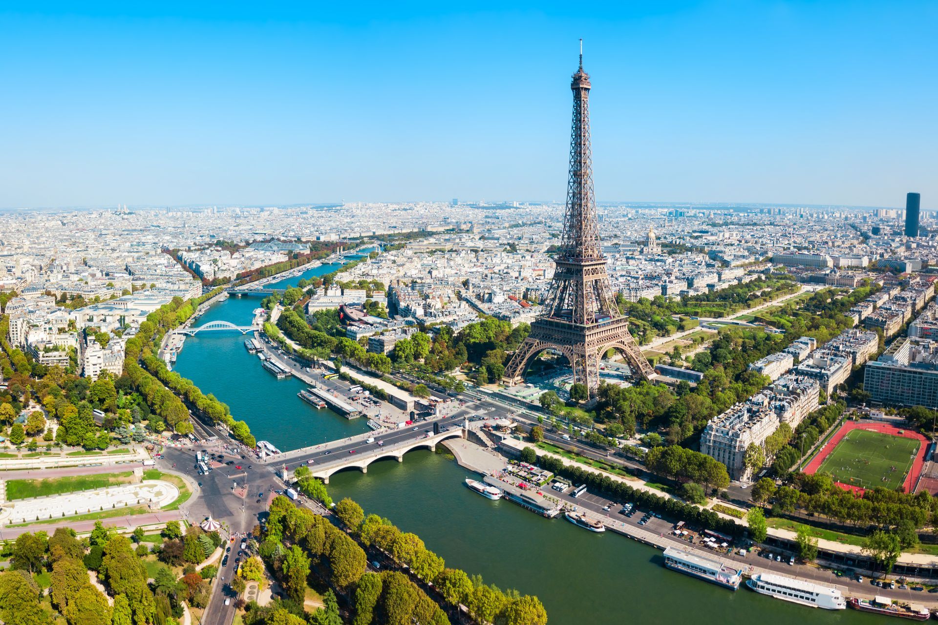 Vue aérienne de la tour Eiffel et de la Seine à Paris sous un ciel bleu dégagé.