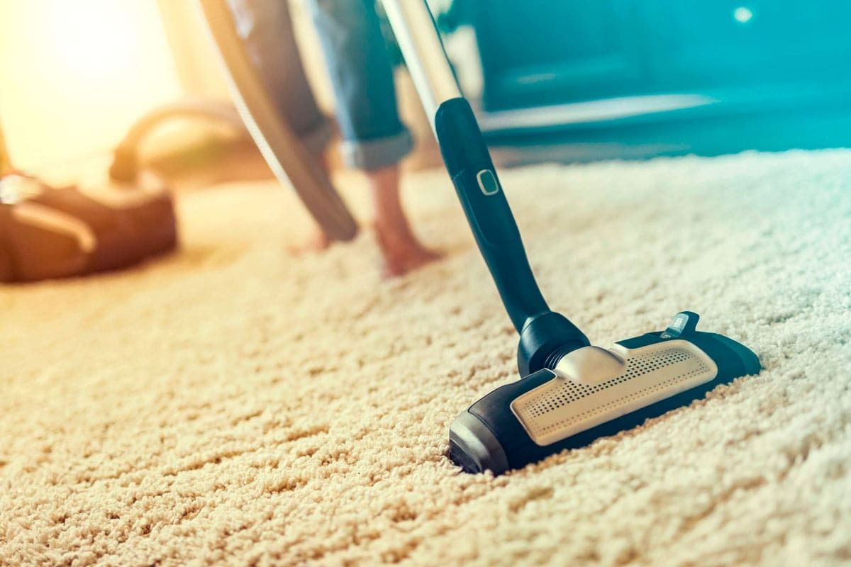 Una persona está usando una aspiradora para limpiar una alfombra.