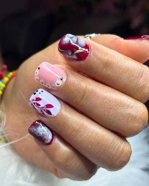 Primer plano de una mano con uñas decoradas en color rosa, blanco y rojo oscuro.