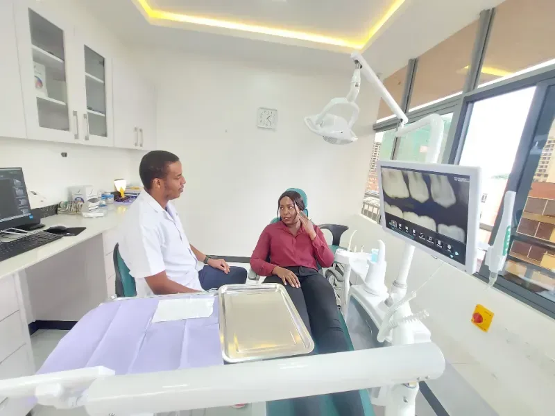 A man and a woman are sitting in a dental chair talking to each other.