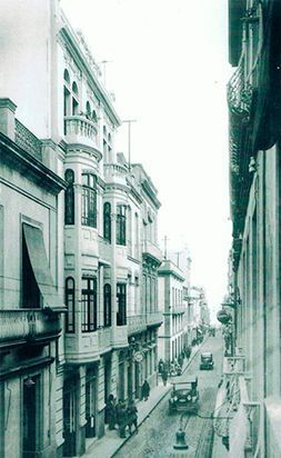 Una fotografía en blanco y negro de una calle de la ciudad con edificios y coches.