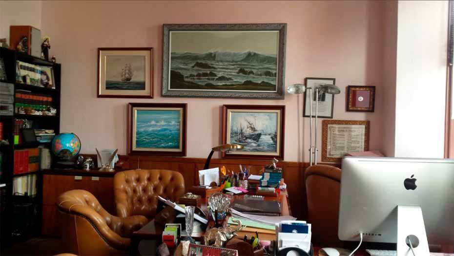 Un escritorio con una computadora Apple en una habitación con pinturas en la pared.