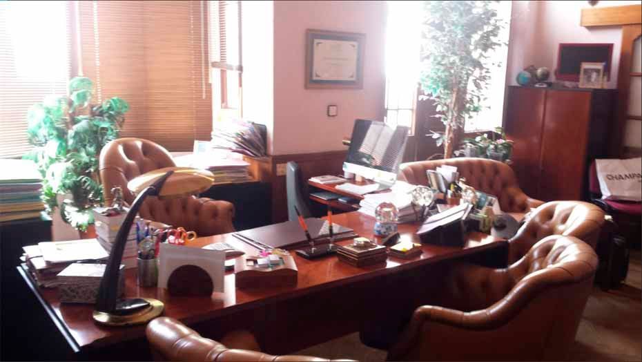 Una oficina muy desordenada con un escritorio y sillas.