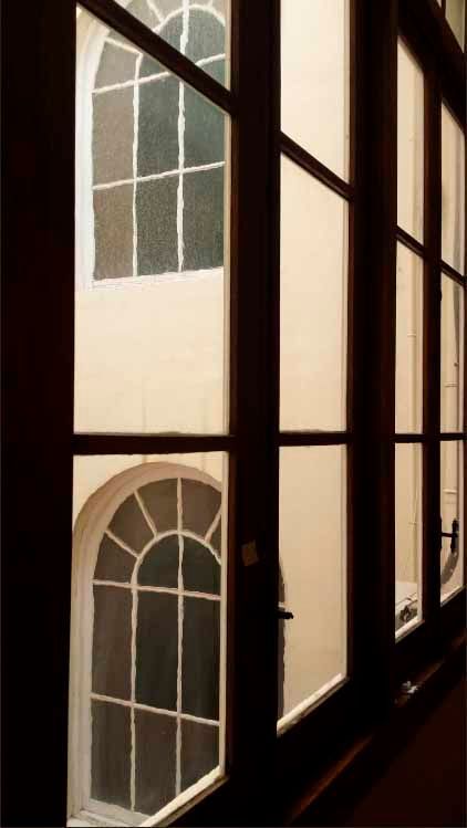 Una vista de un edificio a través de una ventana con ventanas arqueadas.