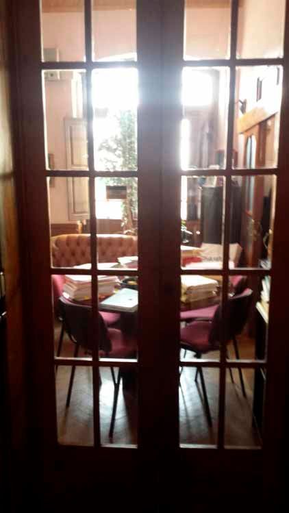 Una habitación con una mesa y sillas detrás de una puerta de vidrio.