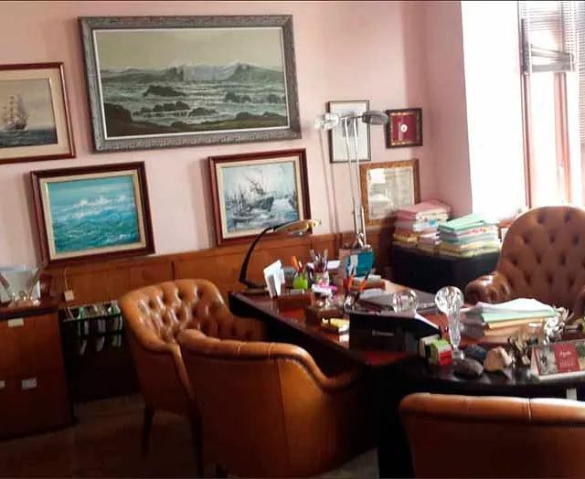 Una habitación con un escritorio, sillas y cuadros en la pared.