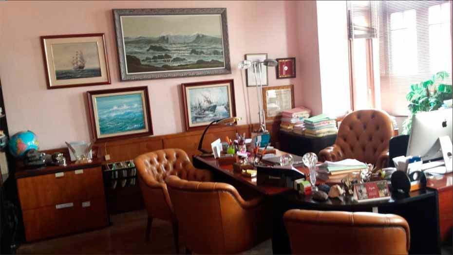 Una habitación con un escritorio y sillas y cuadros en la pared.